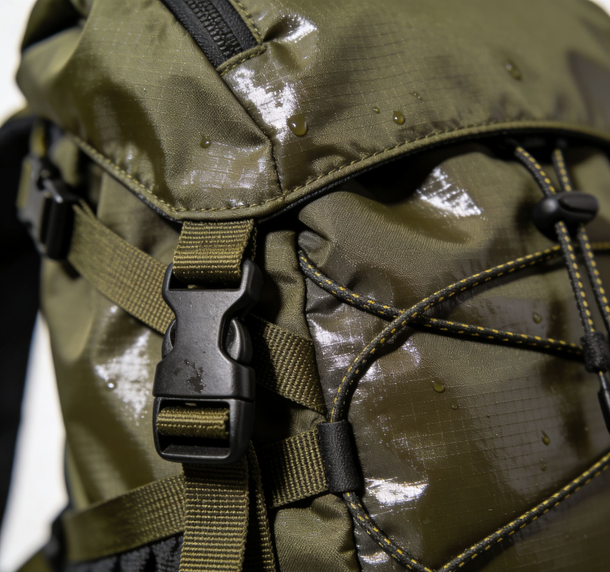 Dùin suas de aodach ripstop dìon-uisge air baga coiseachd a’ sealltainn boinneagan uisge agus fuaigheal ath-neartaichte.